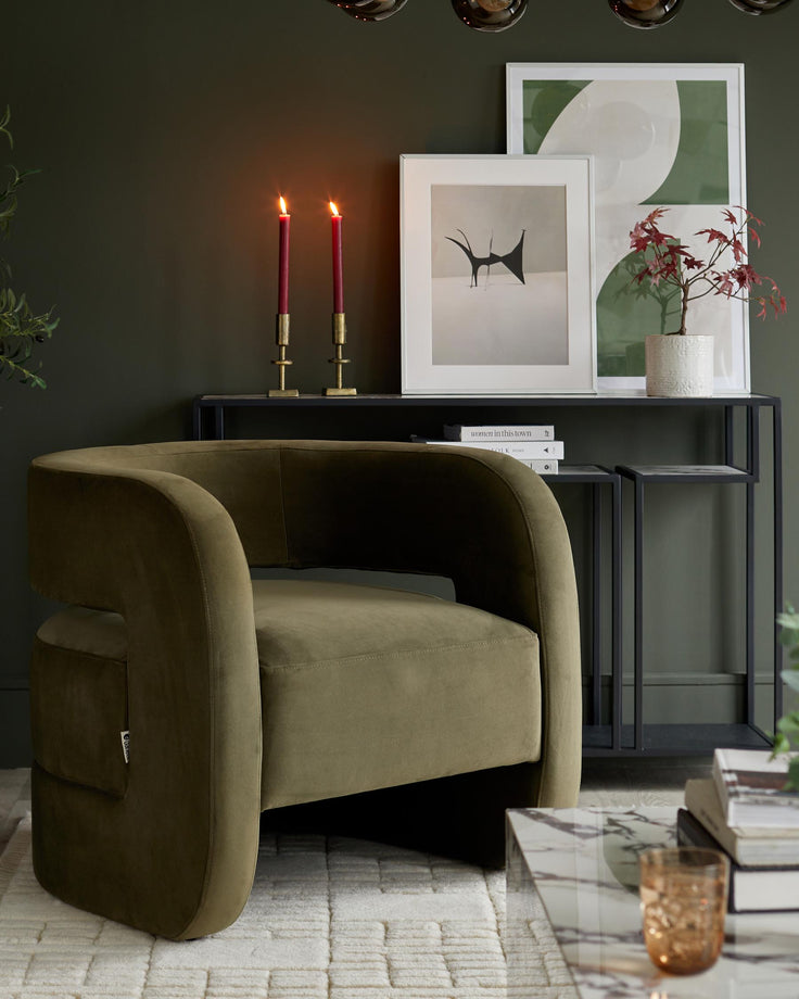 An olive green armchair sits next to a black console table with artwork and candles, offering a luxurious, stylish living space.