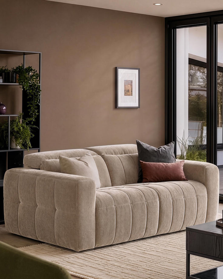 Skye 2-seater sofa in champagne fabric with quilted channel detailing, shown in a neutral living room setting with accent pillows.