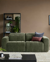 Skye 2-seater sofa in dark green fabric with quilted seat cushions and curved arms, styled in a modern living room.