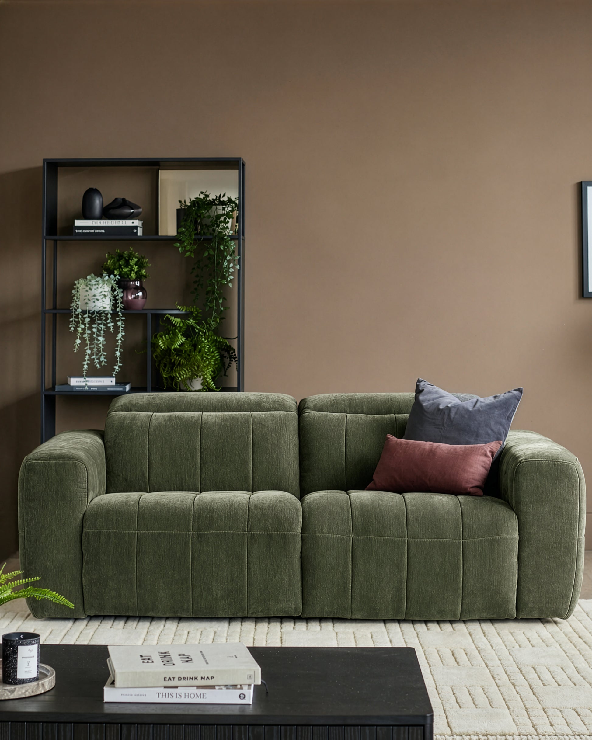 Skye 2-seater sofa in dark green fabric with quilted seat cushions and curved arms, styled in a modern living room.