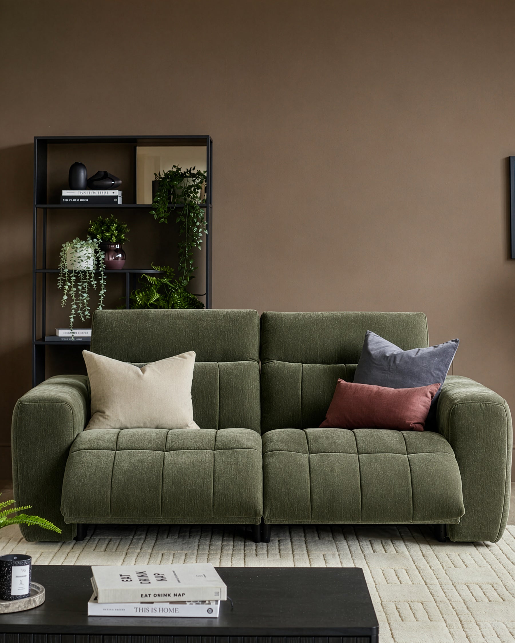 Skye 2-seater sofa in dark green fabric with quilted seat cushions, rounded arms, and black legs, styled in a living room setting.