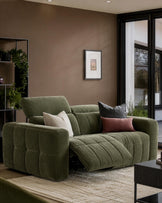 Skye 2-seater sofa in dark green fabric with quilted cushioning, displayed in a modern living room setting with decorative pillows.