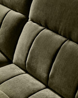 Close-up of dark green fabric sofa showing quilted cushioned backrest and seat detail.