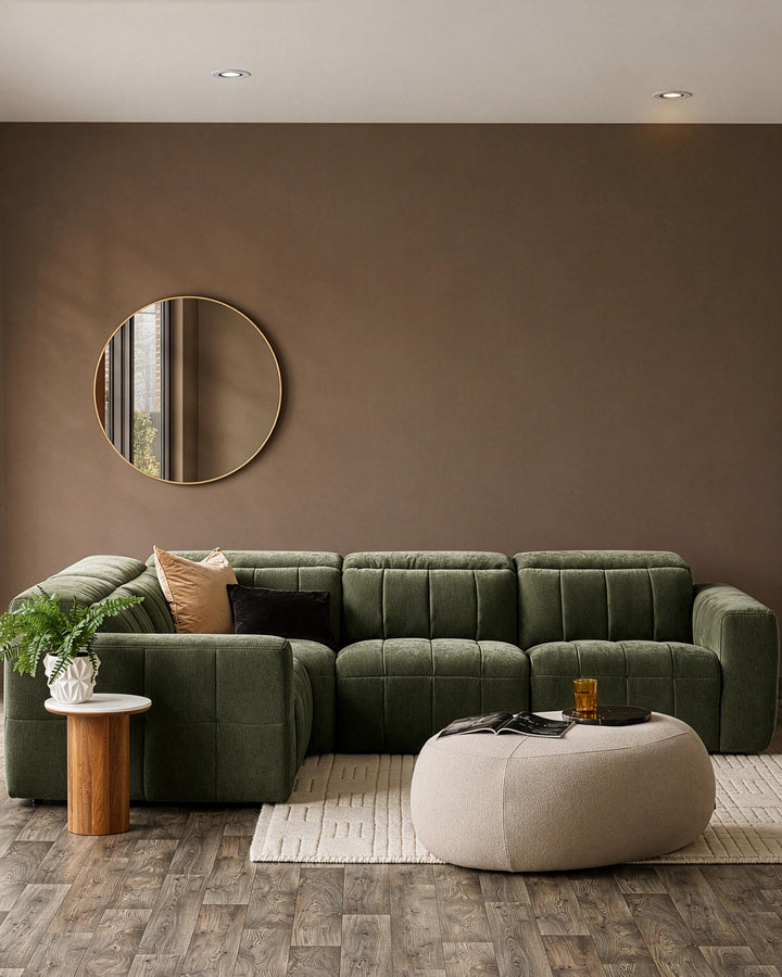 Dark green quilted fabric corner sofa in modern living room setting with neutral walls and wooden flooring.