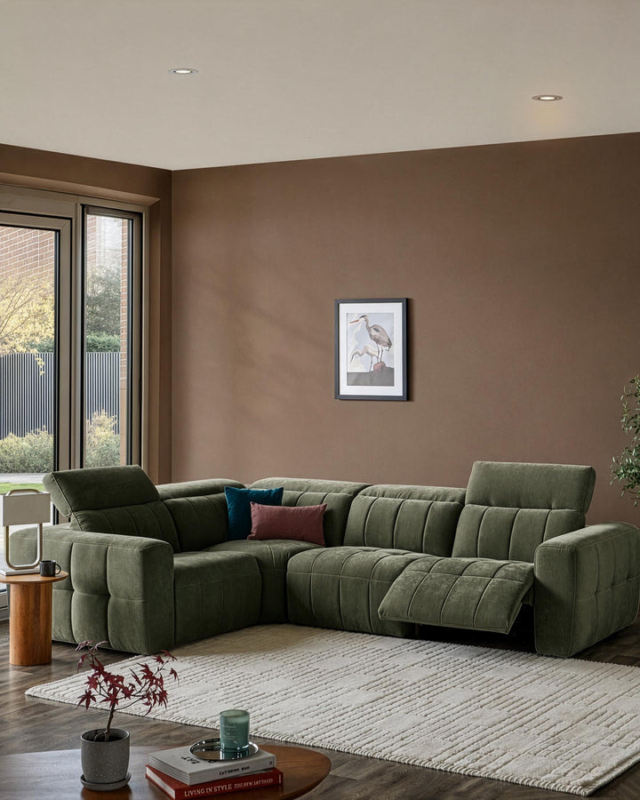 Skye small corner sofa in dark green fabric with quilted seat cushions, positioned in a modern living room with warm brown walls.