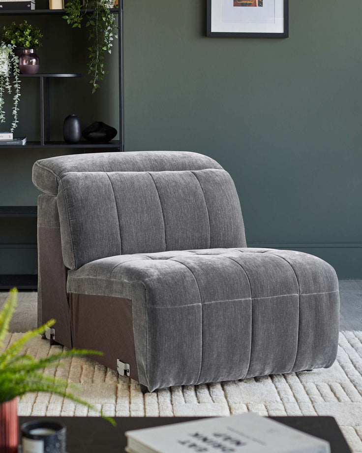 Grey single sofa bed with buttoned design on a patterned rug, bookcase in background