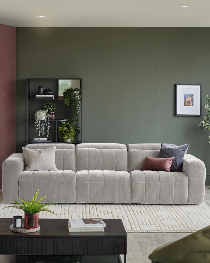 A plush, grey sofa with plump cushions sits atop a patterned rug in a stylish, modern living room.