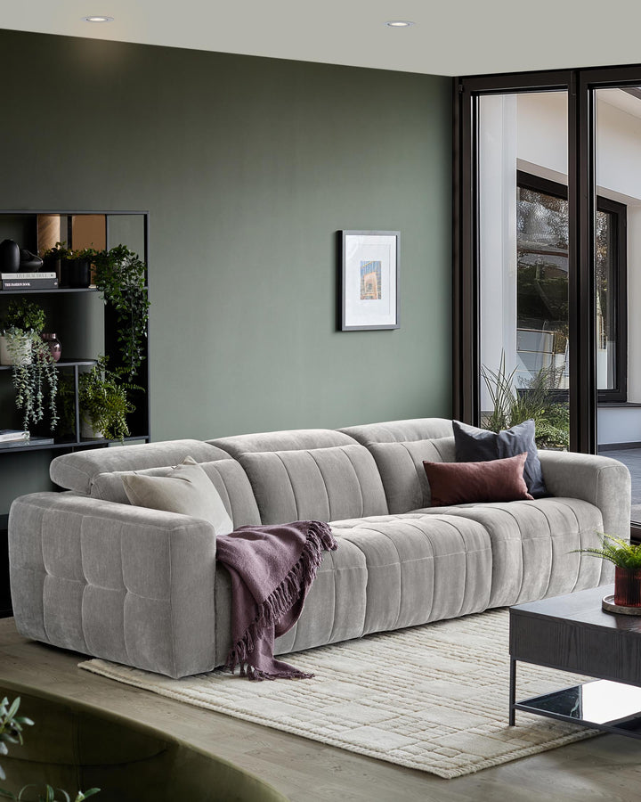 Grey modular sofa with cushions and a throw, coffee table, shelving unit, and an abstract print on the wall.