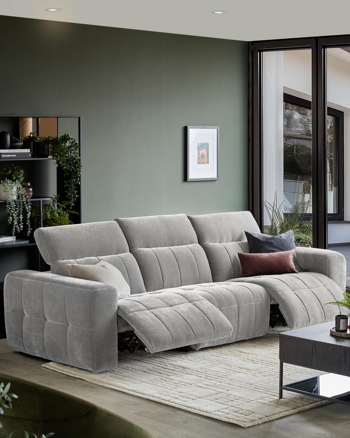 A comfy grey three-seater sofa with recliner seats, styled with cushions, sits on a neutral rug in a modern living room.