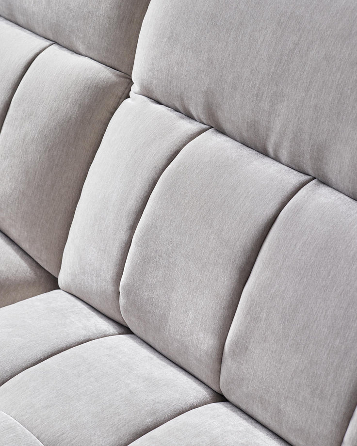 Close-up of a modern, light grey sofa with deep cushions and a textured fabric finish.