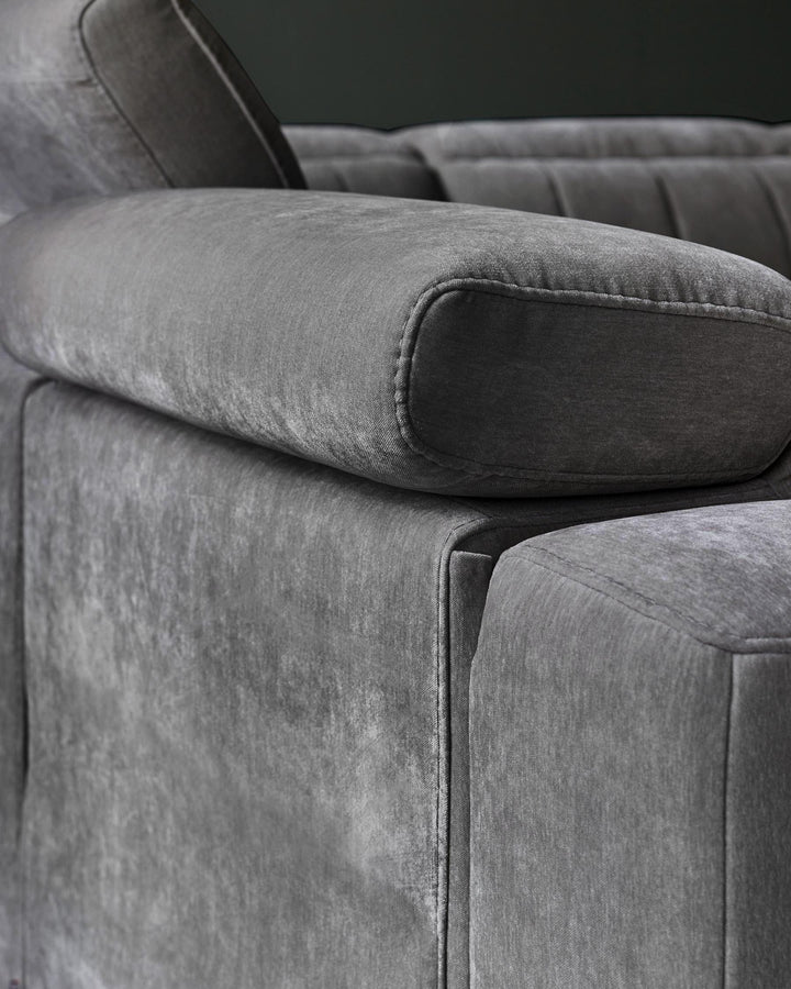 A close-up of a plush gray sofa, featuring thick arms and soft cushions, showcasing modern design and luxurious fabric.