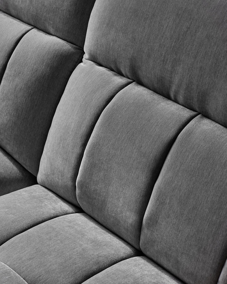 Close-up of a plush, gray upholstered sofa with a modern design, featuring thick, soft cushions for comfort and style.
