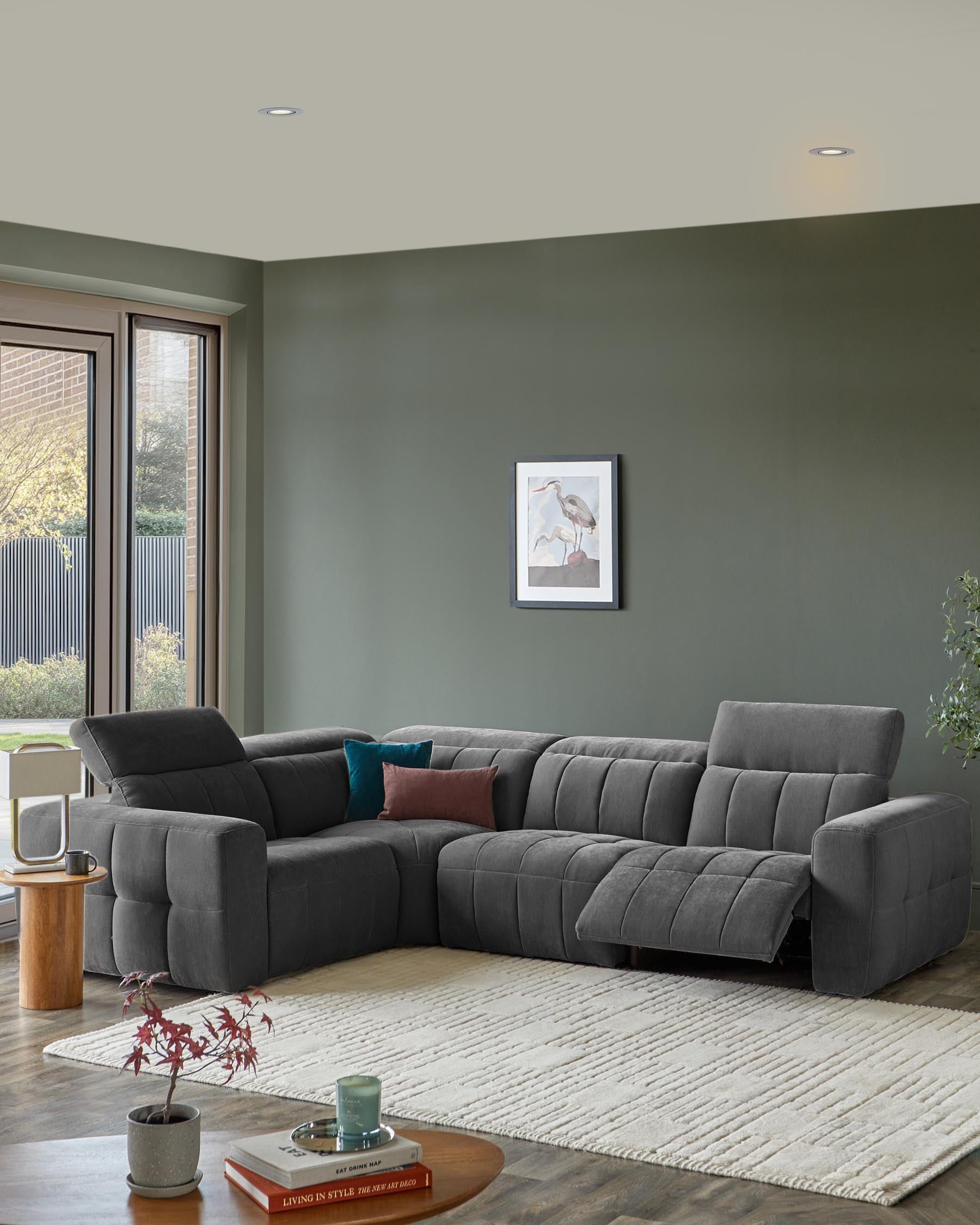 Modern grey sectional sofa with tufted design, accented by cushions, a round wooden side table, and a cream textured rug.