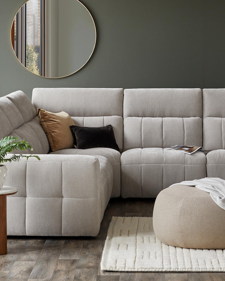 Modern sectional sofa in light fabric, accented with plush pillows, paired with a round mirror, a soft rug, and an ottoman.