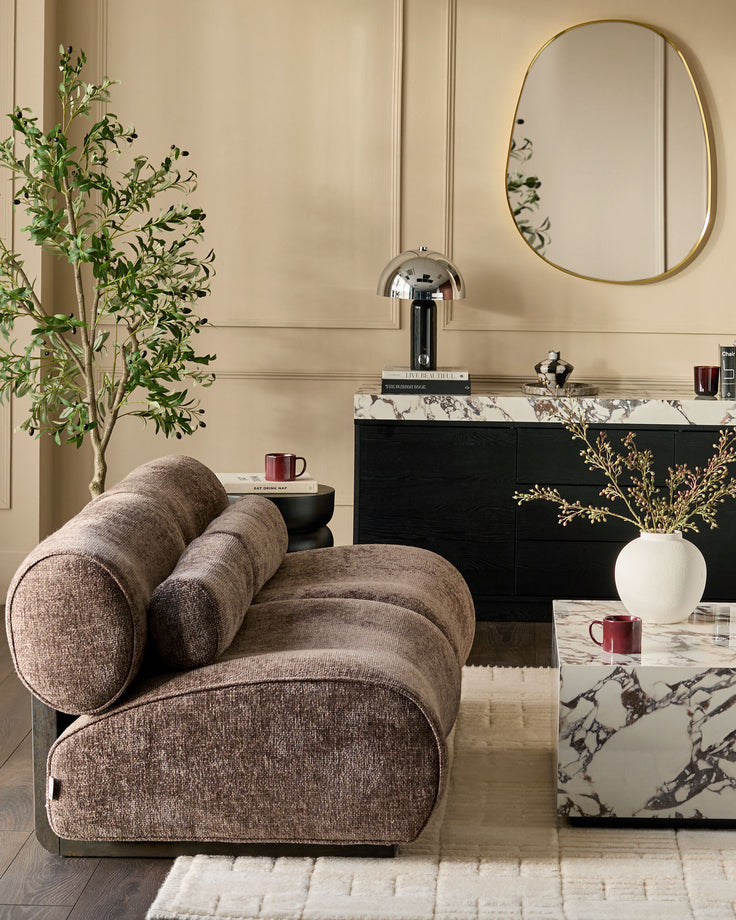 Sofia 2-seater sofa in mocha fabric with curved cylindrical armrests, displayed in a styled living room setting.