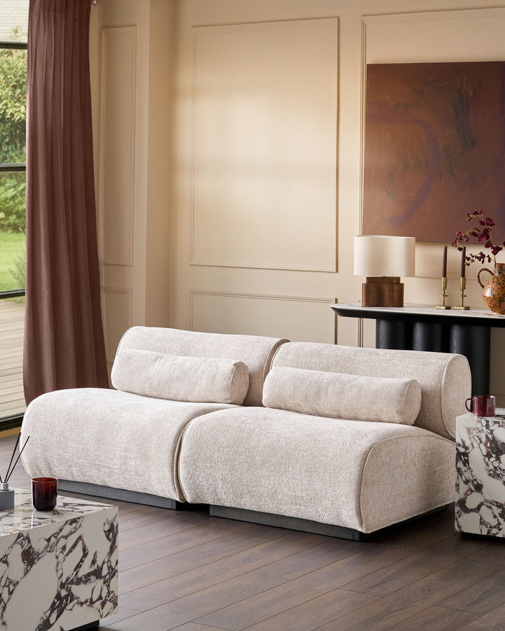 Sofia 2-seater sofa in natural fabric with cylindrical armrests and bolster pillows, displayed in a contemporary living room setting.