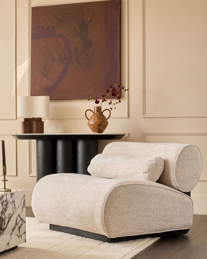 Sofia accent chair in natural fabric with curved rolled arms and black base, styled in modern living room.