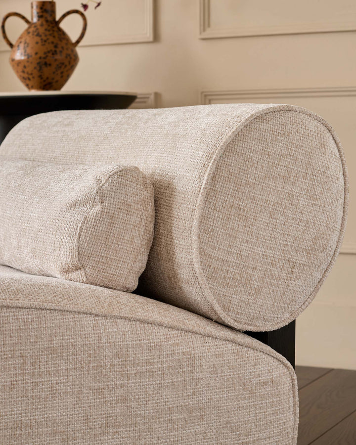 Sofia 2-seater sofa in natural fabric, close-up detail showing cylindrical bolster pillows and curved upholstered armrest.