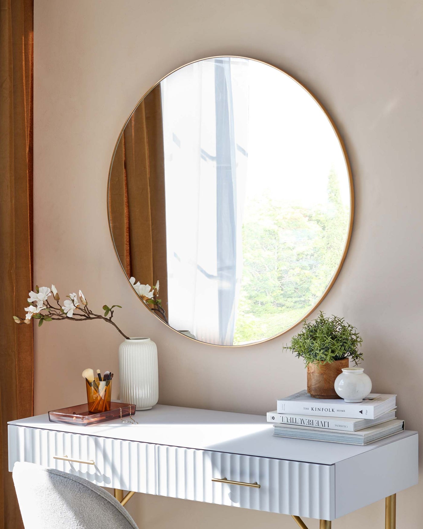 Elegant modern console table with a white grooved front, featuring gold handles, paired with a minimalist round wall mirror with a bronze frame.