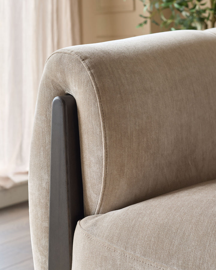 Close-up of champagne fabric upholstery and dark wooden arm detail on Teagan two-seater sofa.