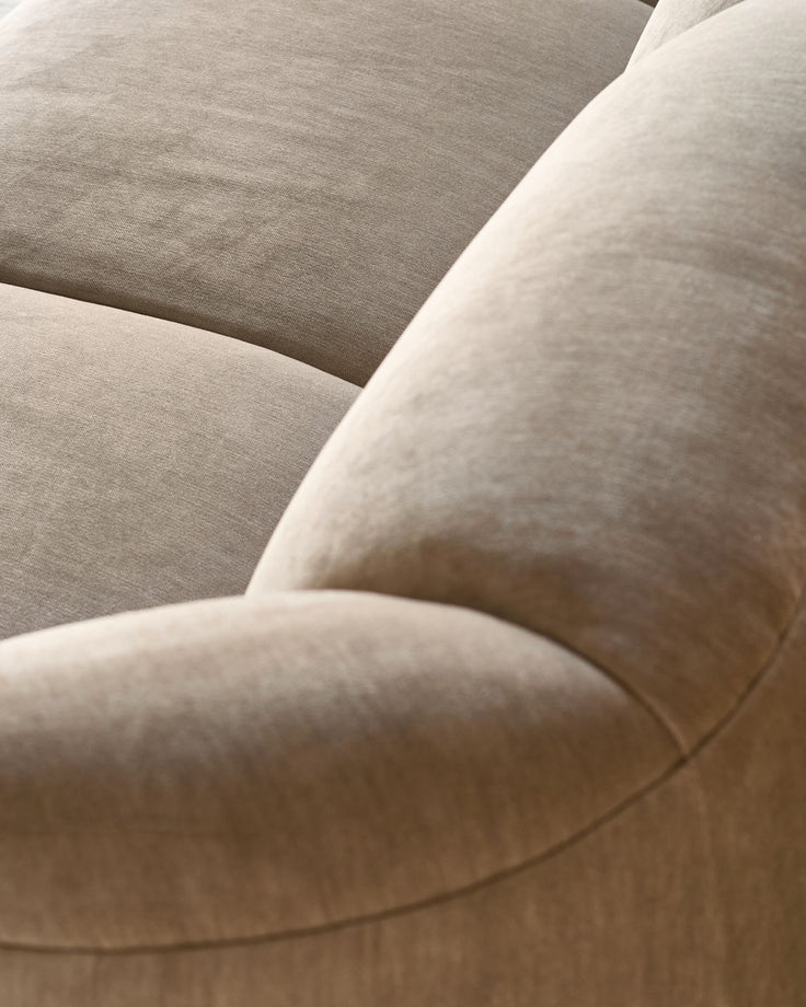 Teagan 2-seater sofa in champagne fabric, close-up detail of curved armrest and seat cushion.