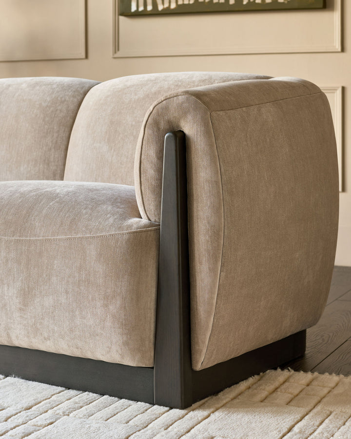 Teagan 2-seater sofa in champagne fabric, showing curved armrest detail with dark wood frame accent.