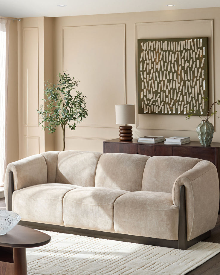 Teagan 3-seater sofa in champagne fabric with curved arms and dark wood base in a neutral living room setting.