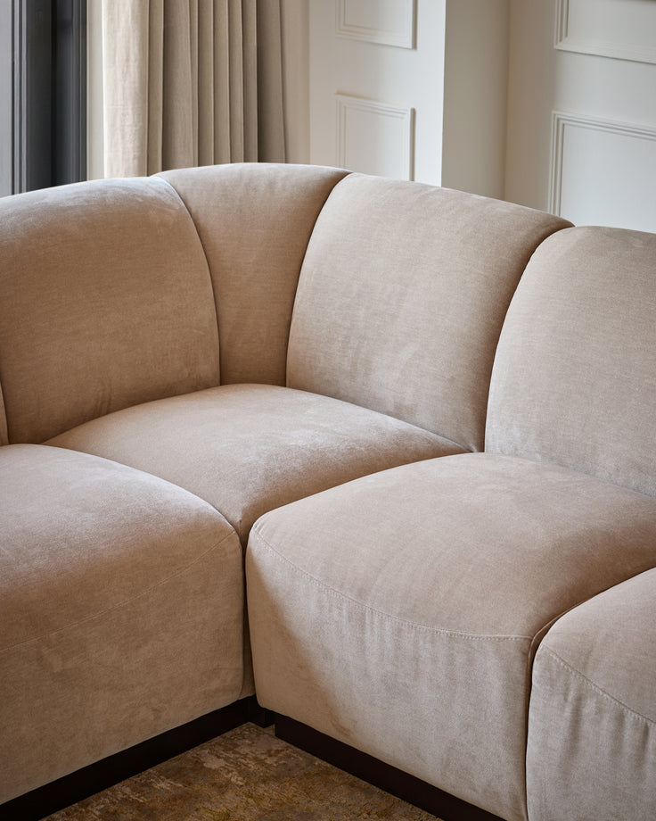 Teagan left-hand small corner sofa in champagne fabric, showing curved modular design with rounded armrests and piped seams.