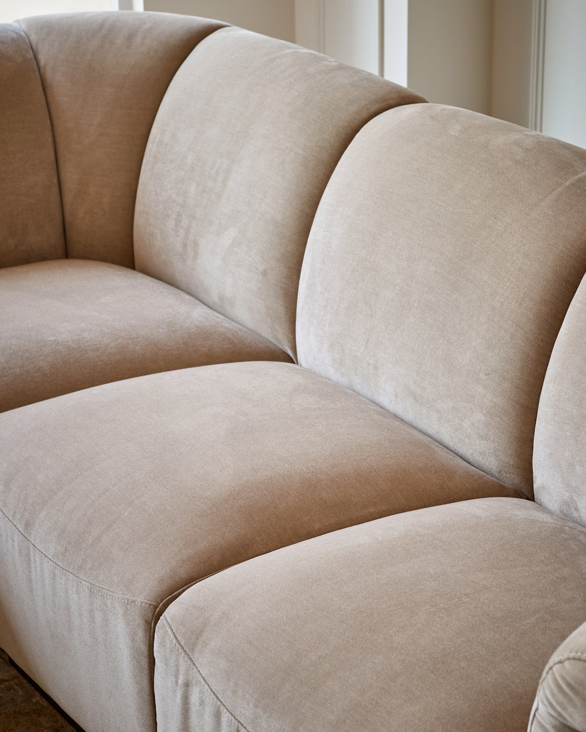 Teagan left-hand small corner sofa in champagne fabric, showcasing curved cushioned sections and soft upholstery detail.