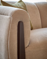 Teagan left-hand small corner sofa in champagne fabric, close-up of rolled arm with dark wooden leg detail.