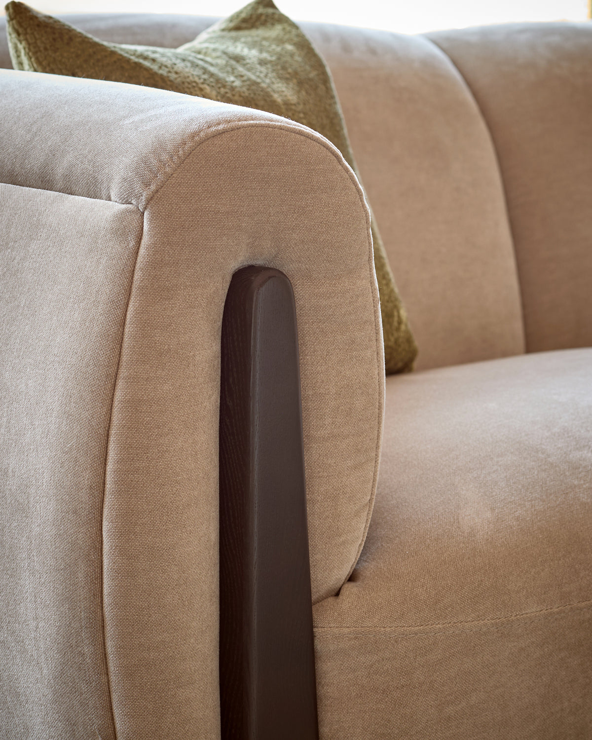 Teagan left-hand small corner sofa in champagne fabric, close-up of rolled arm with dark wooden leg detail.