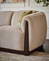 Teagan left-hand small corner chair in champagne fabric with dark wood frame detail, shown at side angle.
