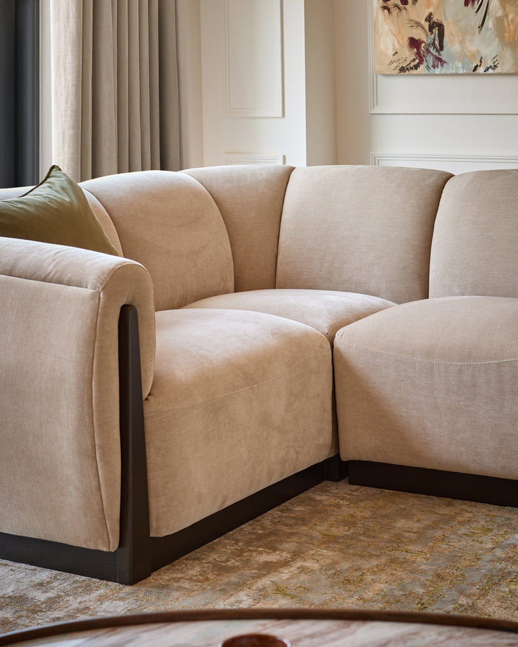 Teagan left-hand small corner sofa in champagne fabric with dark wooden base, angled view in neutral living room setting.