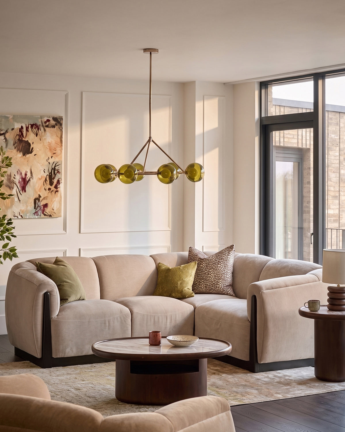 Champagne fabric right-hand corner sofa in modern living room setting with curved arms and rounded base.