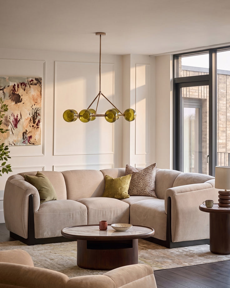 Champagne fabric right-hand corner sofa in modern living room setting with curved arms and rounded base.