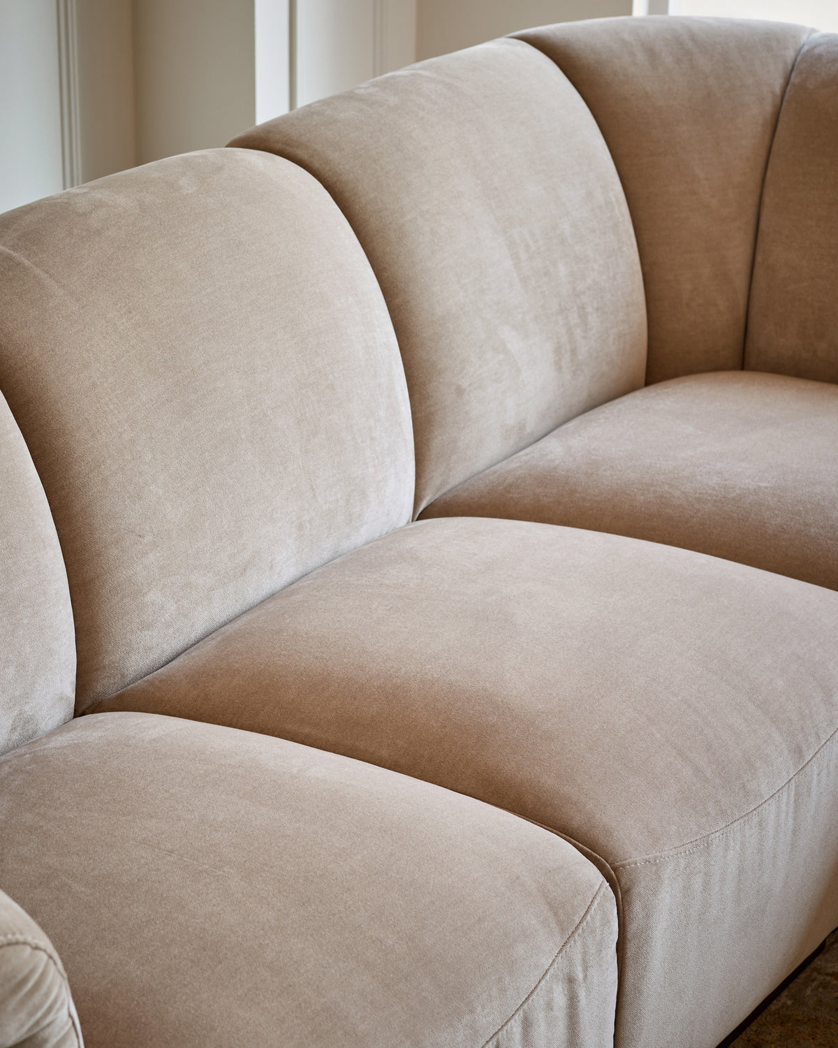 Teagan right-hand small corner sofa in champagne fabric, showing curved cushioned sections and clean modern design.