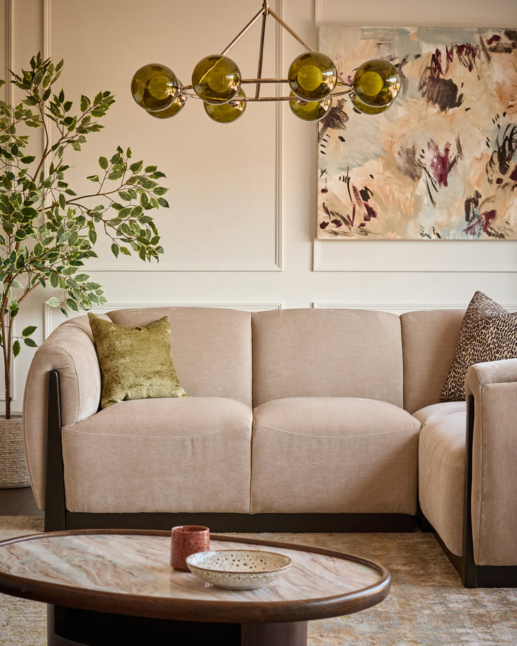Champagne fabric right-hand corner sofa in a modern living room setting with olive green pendant light and abstract artwork.