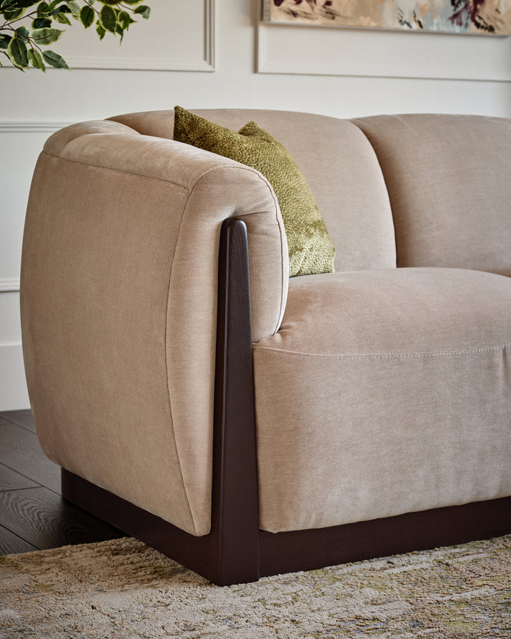 Teagan right-hand small corner chair in champagne fabric with curved arms and dark wood base detail, styled with olive cushion.