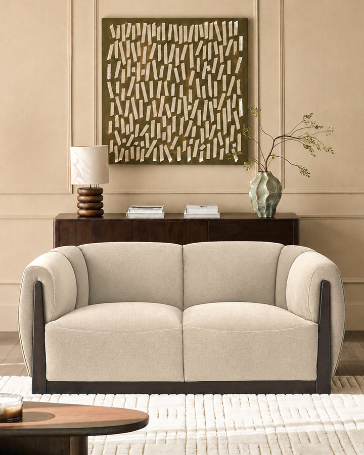 Teagan 2-seater sofa in champagne fabric with dark wood frame and curved armrests, displayed in a styled living room.