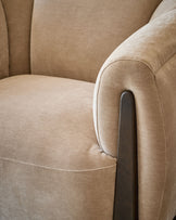 Teagan armchair in champagne fabric, close-up detail of curved arm with dark wood handle and stitched seam.