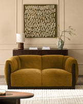 Teagan 2-seater sofa in ochre fabric with curved arms and black wooden frame, styled in a modern living room setting.