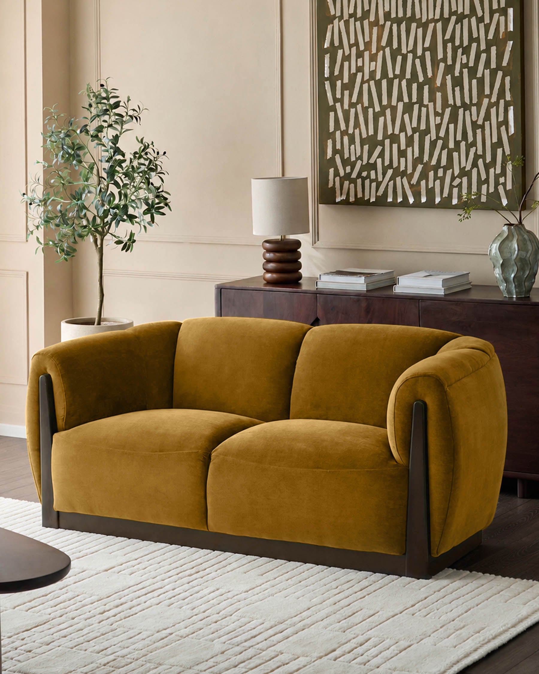 Teagan 2-seater sofa in ochre fabric with curved arms and dark wood base, shown in living room setting.