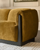 Teagan 2-seater sofa in ochre fabric with curved armrests and dark wooden legs, shown from side angle on a neutral rug.