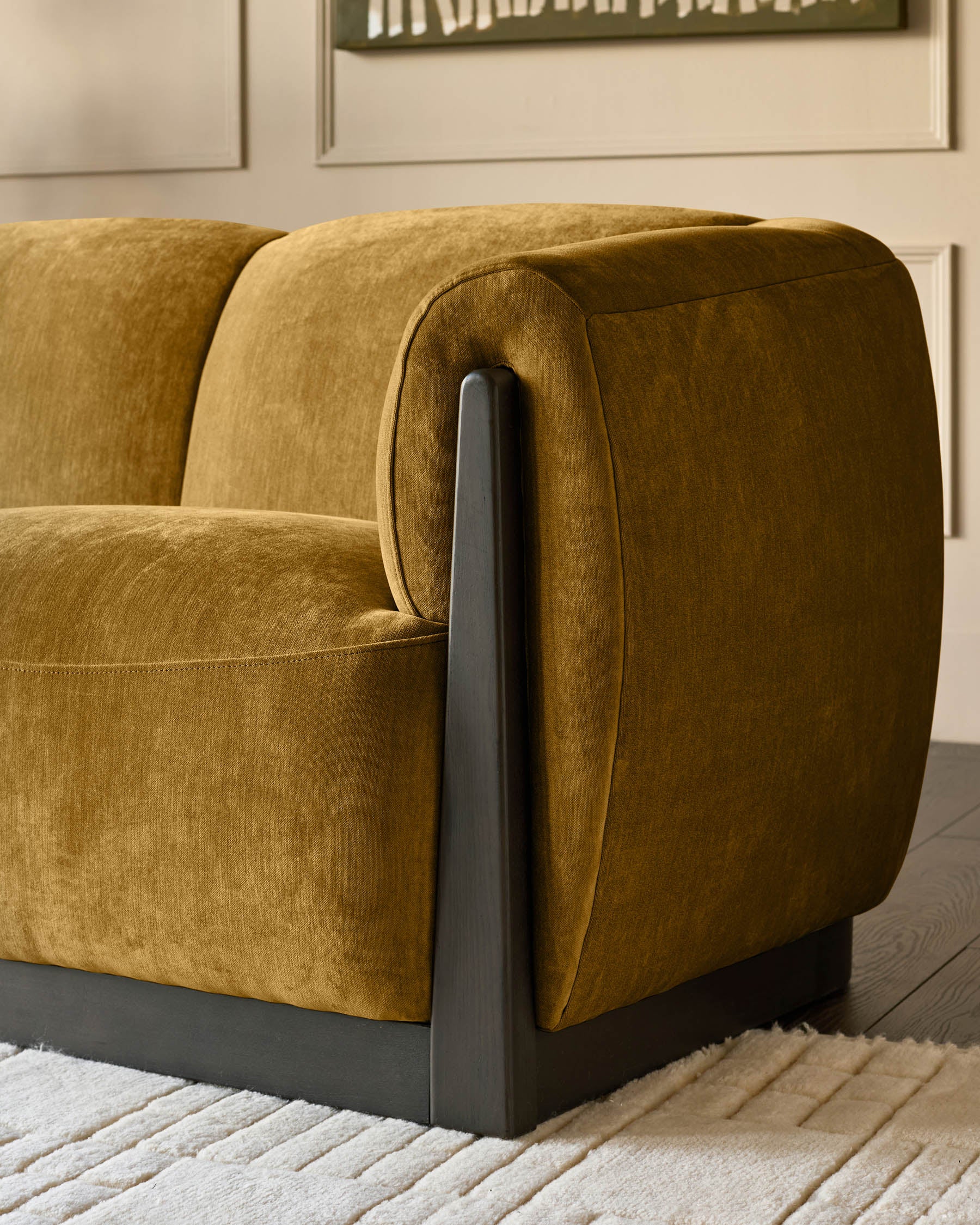 Teagan 2-seater sofa in ochre fabric with curved armrests and dark wooden legs, shown from side angle on a neutral rug.