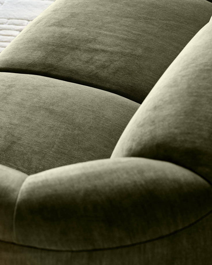 Close-up of Teagan 2-seater sofa in olive green fabric, showing curved armrest and cushioned seating detail.