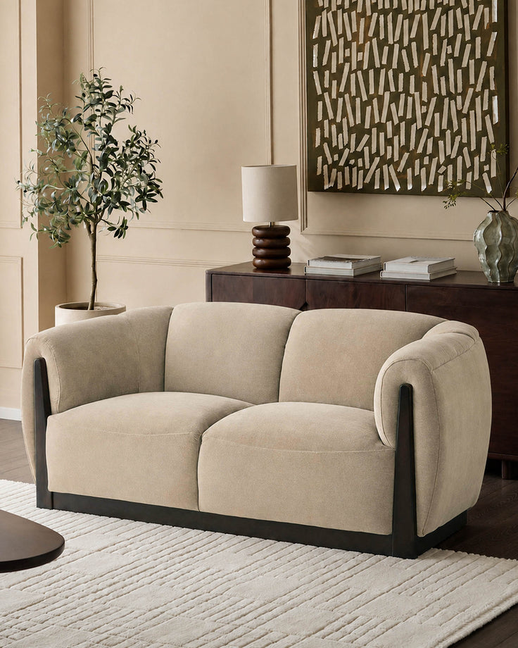 Teagan 2-seater sofa in champagne fabric with curved arms and black wooden base, styled in neutral living room setting.