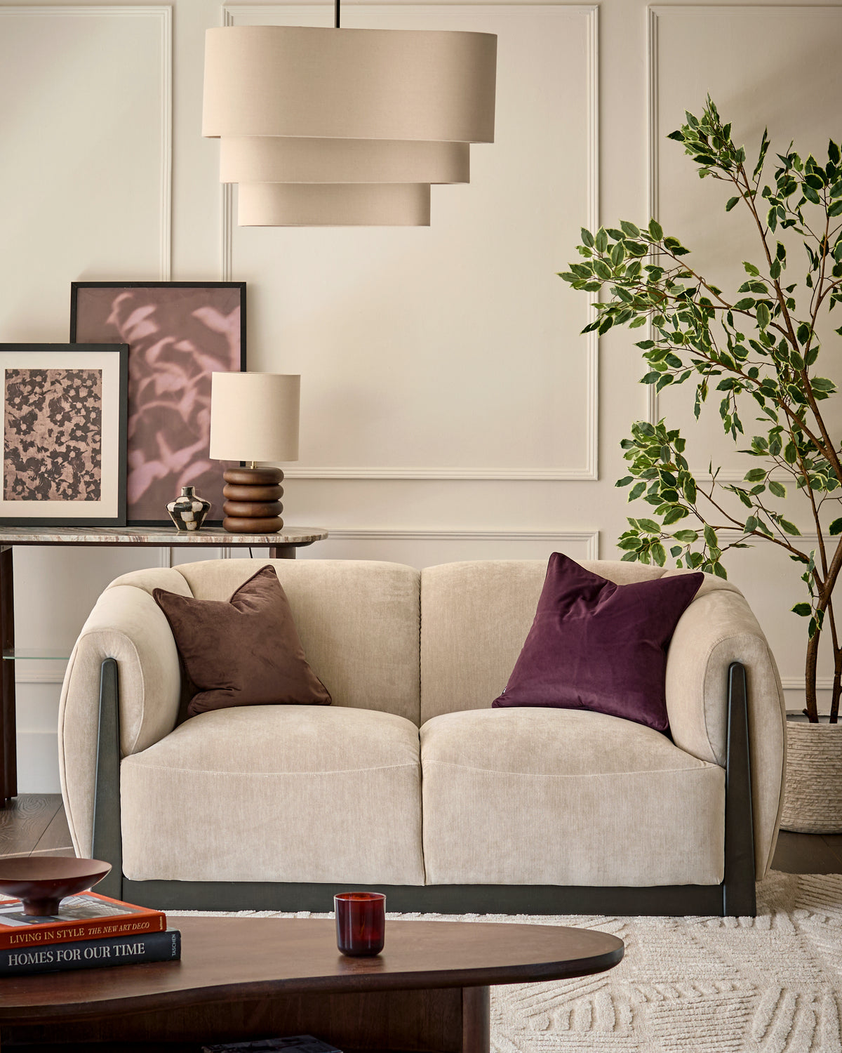 Teagan 2-seater sofa in champagne fabric with curved armrests and dark wood base, styled in a modern living room setting.