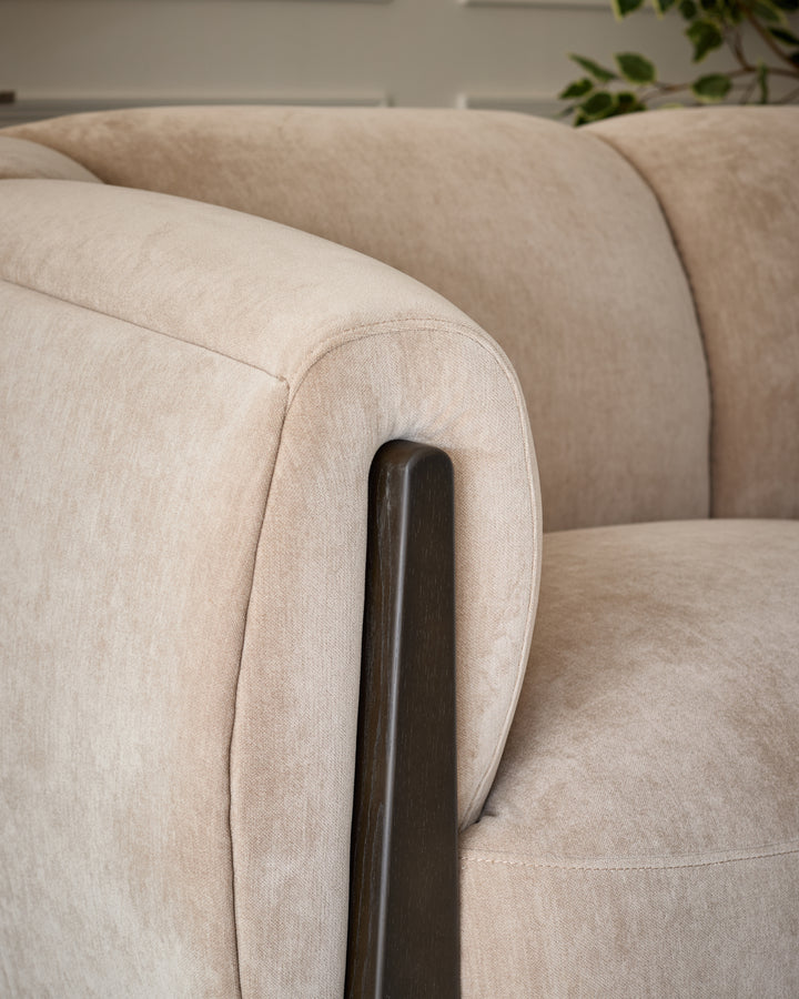 Teagan 2-seater sofa in champagne fabric, close-up detail of curved armrest with dark wood handle.