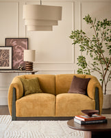 Teagan 2-seater sofa in ochre fabric with curved arms and dark wood accents, styled in a modern living room.