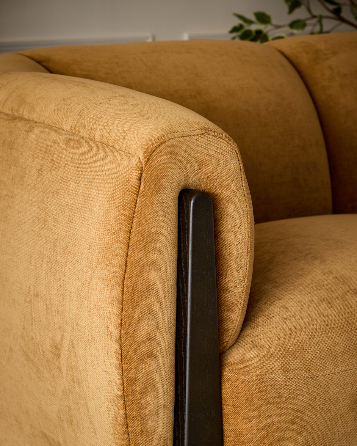 Teagan 2-seater sofa in ochre fabric with dark wooden armrest detail, angled close-up view.